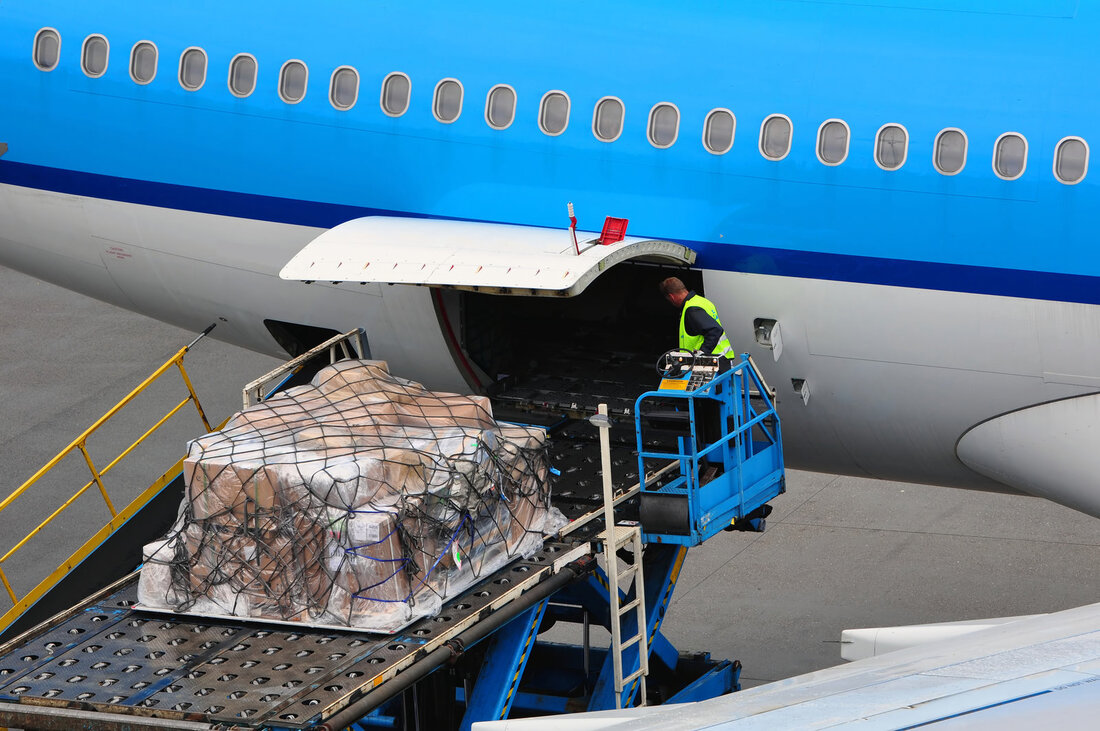 male worker putting the boxes into the plane